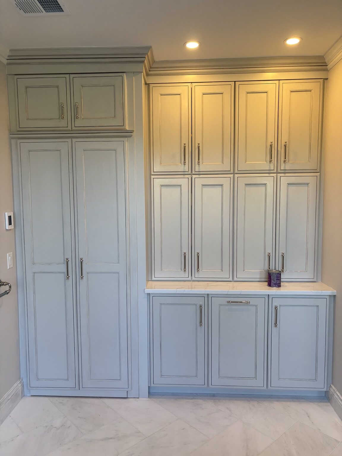 Floor-to-ceiling painted bathroom cabinetry with tall storage and a counter