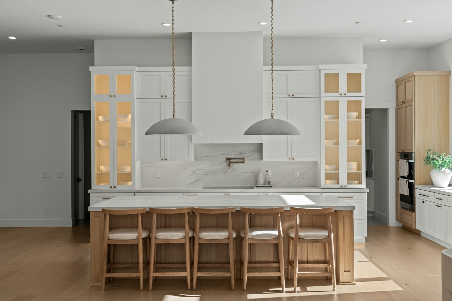 Grand transitional white kitchen with a natural oak island, tall cabinetry, crown molding, and brass accents
